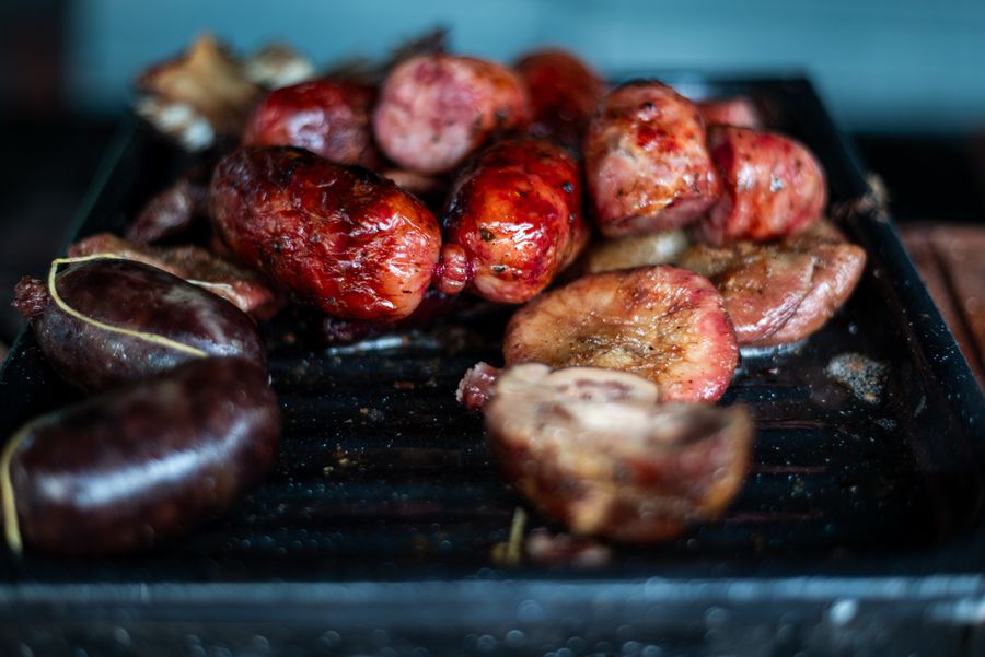 Chorizos y morcillas dorándose sobre la parrilla